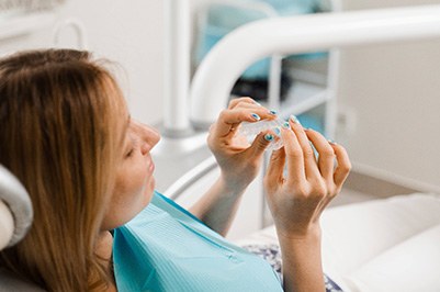Patient holding clear aligner in treatment room