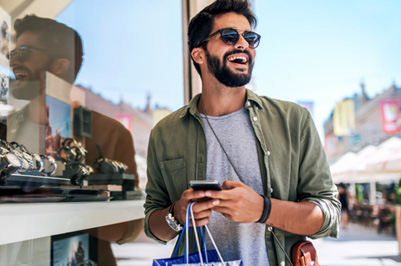 Man with sunglasses smiling while shopping outside