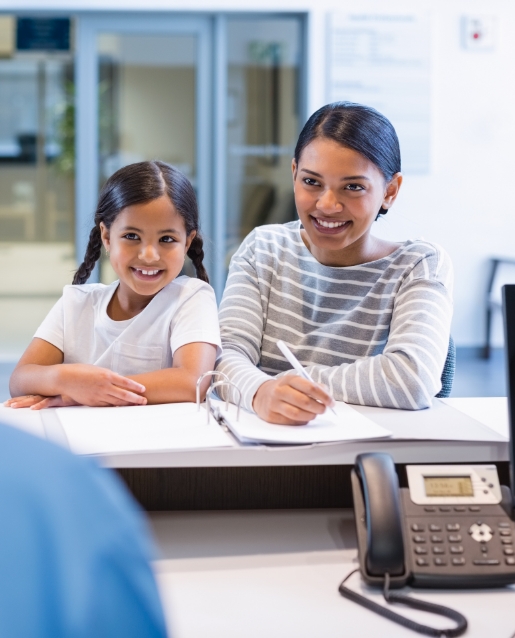 Mother and daughter checking in at front desk of orthodontic office