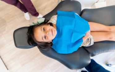 Young girl in dental treatment chair looking up toward the camera