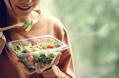 a person eating a salad after removing their clear aligner