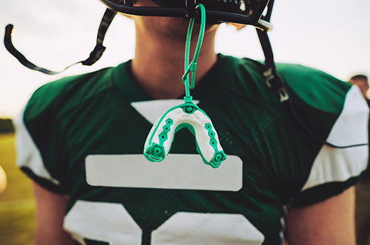 Football player with a sports mouthguard hanging from their helmet