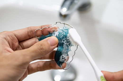 Person brushes their retainer in a sink
