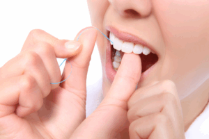 a patient smiling while flossing their teeth